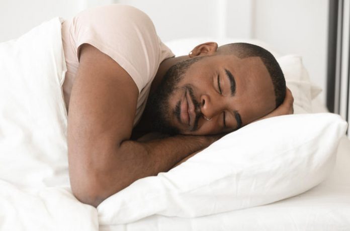 Serene calm young black man sleeping well alone in bed